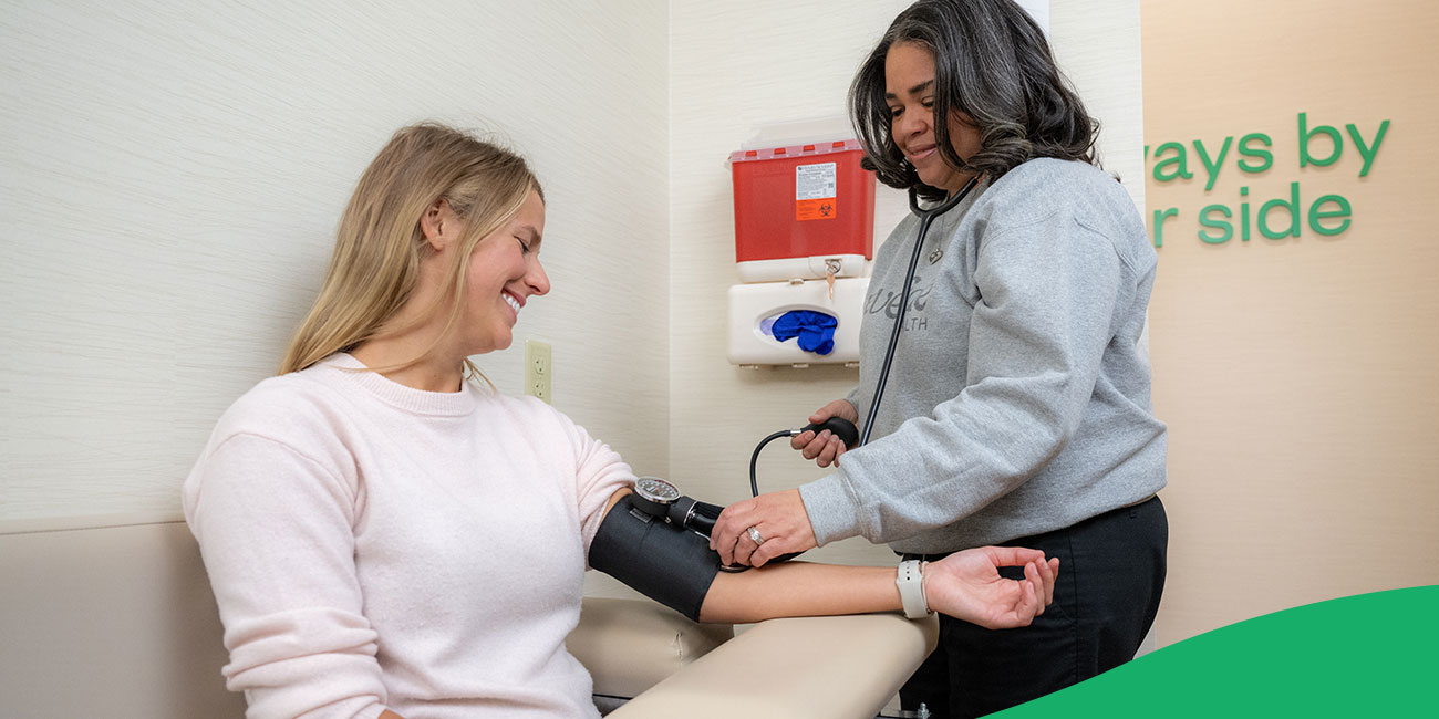 nurse taking blood pressure of patient sitting in a chair