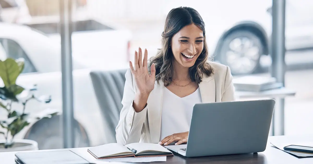 A woman smiling at her laptop during a video interview.