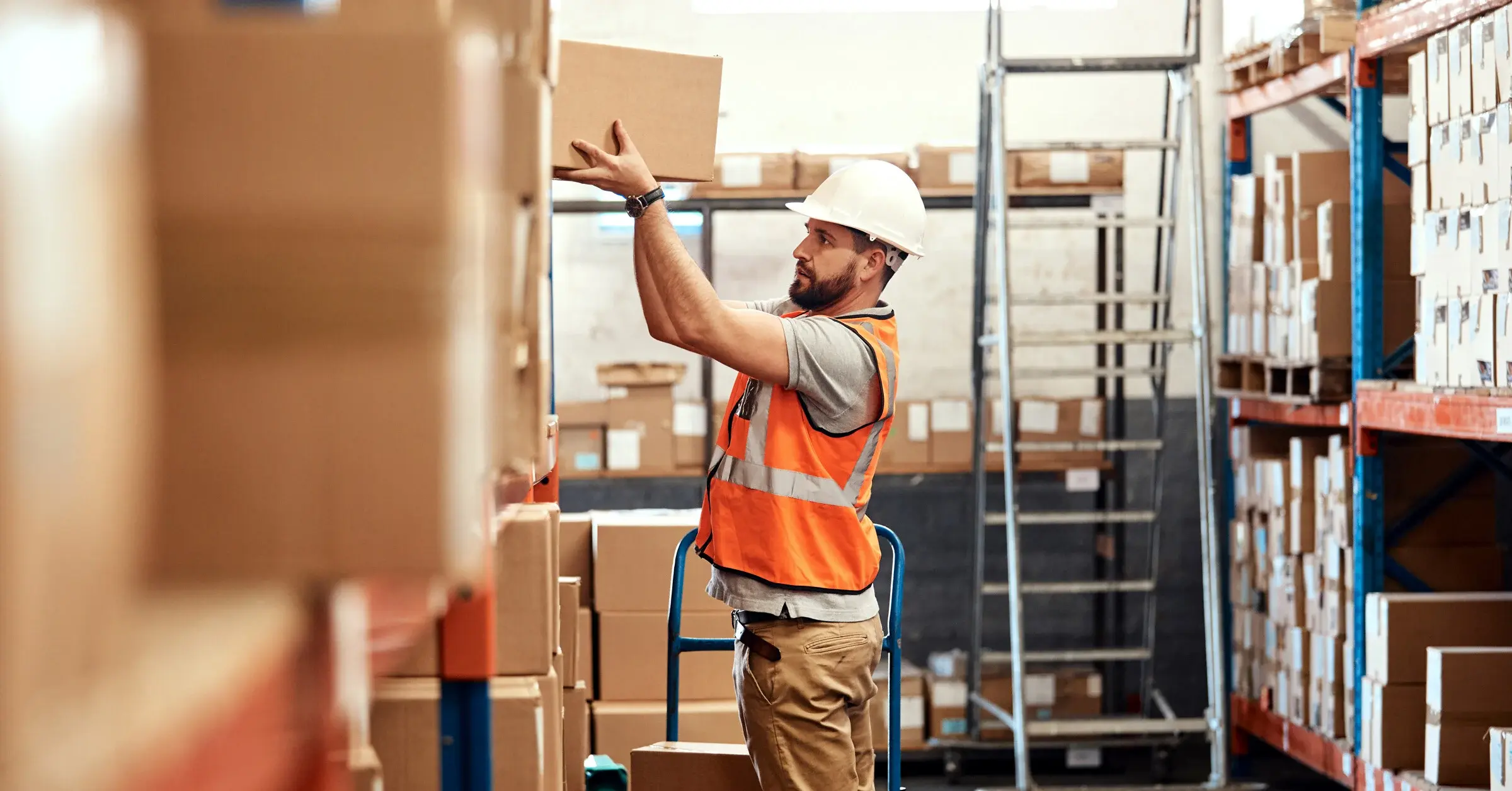 Warehouse worker placing a box on top of a rack.