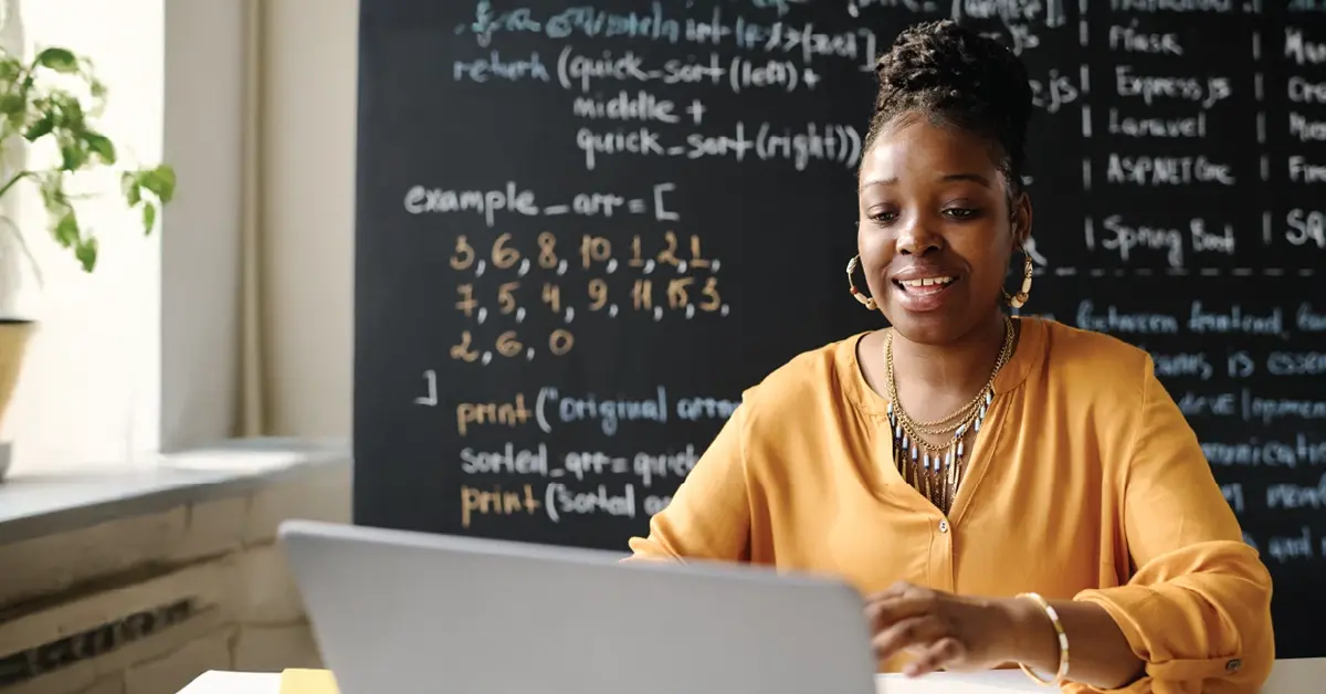 A teacher smiling at her desk while on a virtual healthcare visit with her provider.