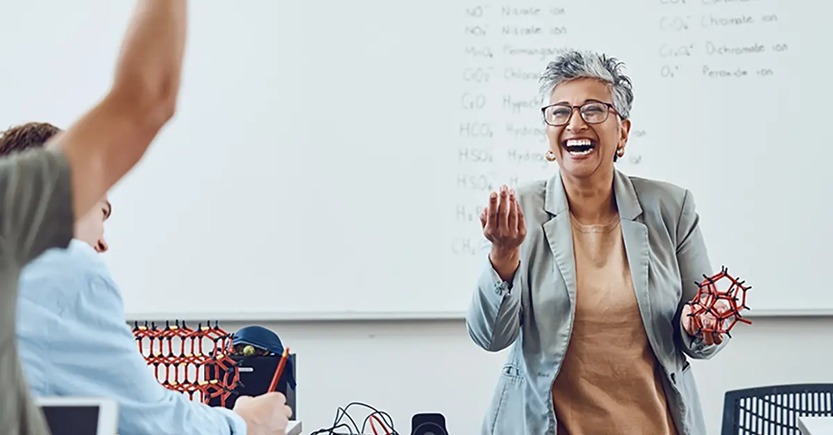 Smiling teacher in a classroom full of students.