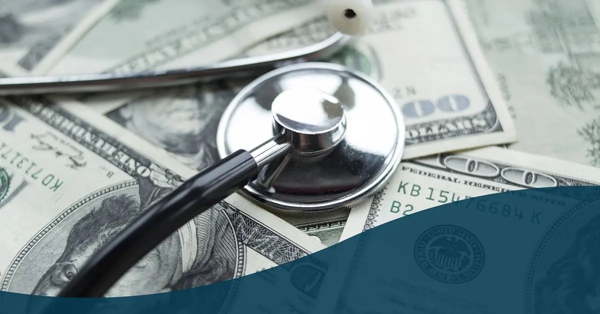 Stethoscope laying on a pile of cash.