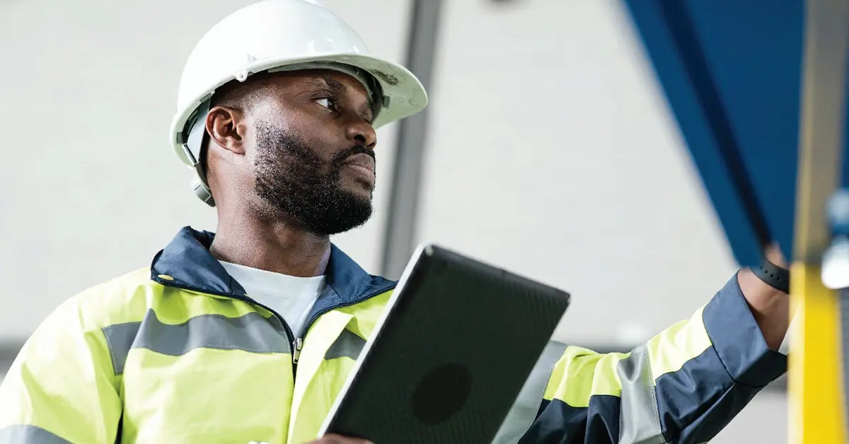 Taft-Hartley worker wearing a hardhat, holding a tablet device.