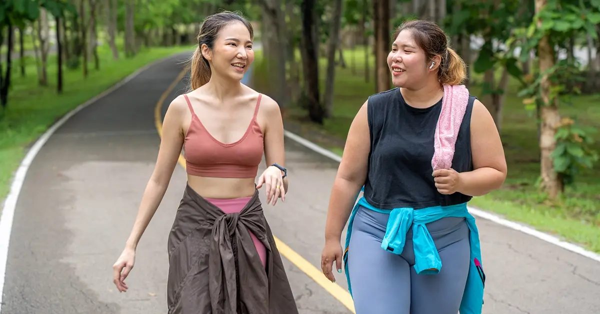 Two women walking in a park in sport outfits.