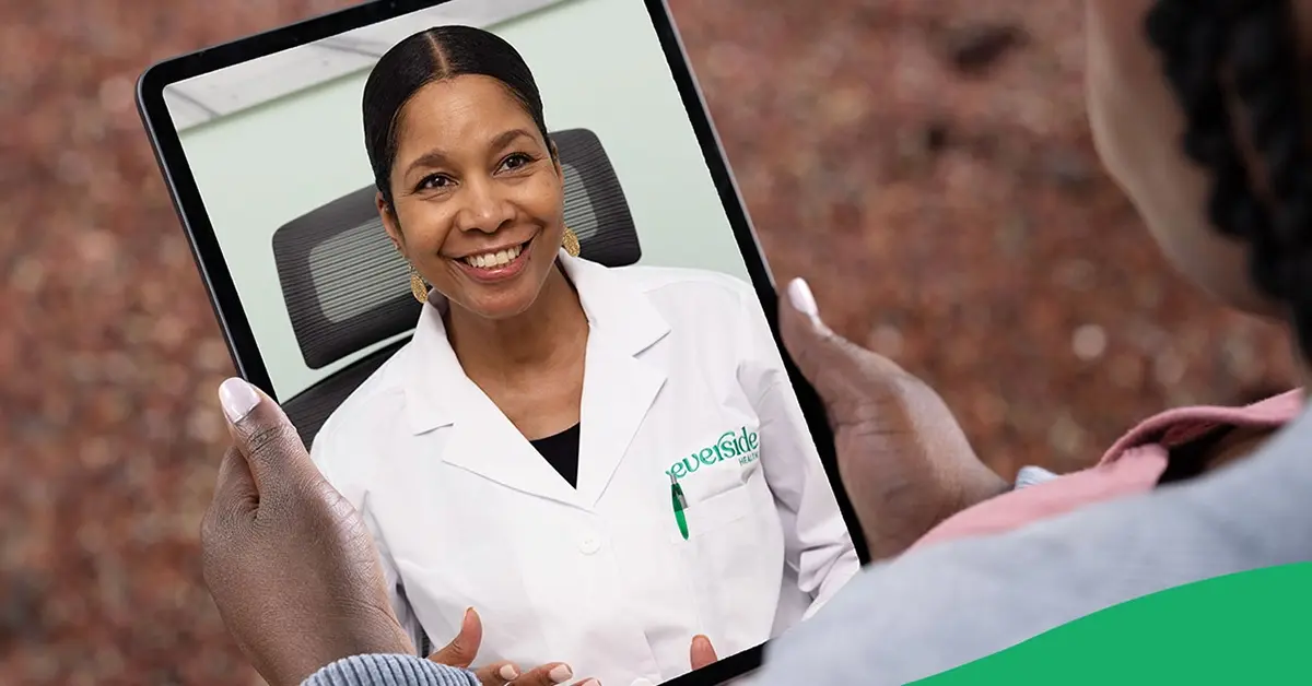 Physician smiling on a tablet screen held by patient.