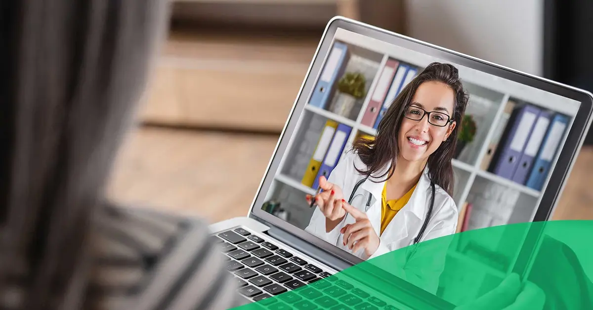 Doctor smiling on a screen during a virtual call with a patient.
